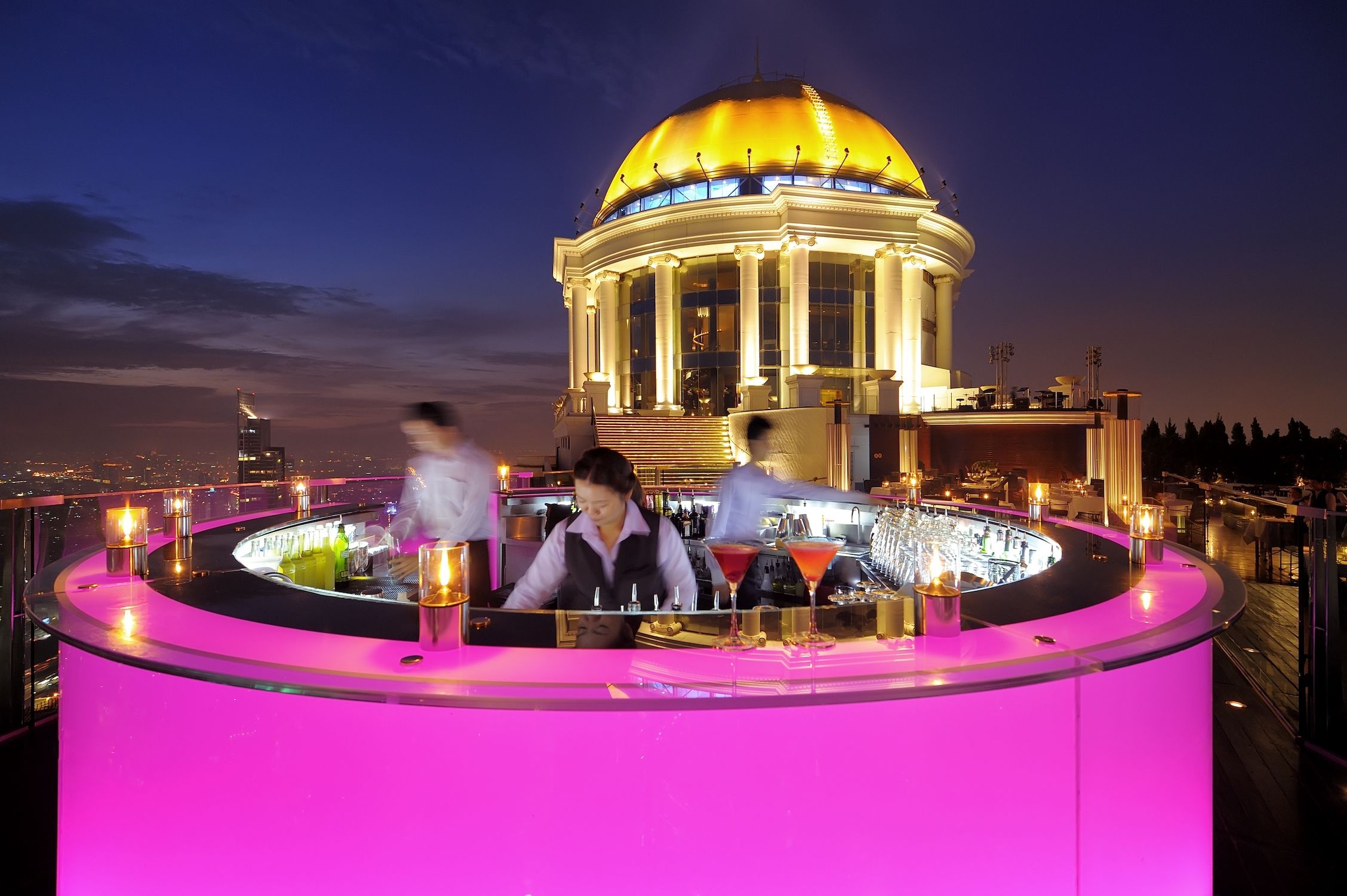 pink light bar by edge of terrace and yellow dome in background