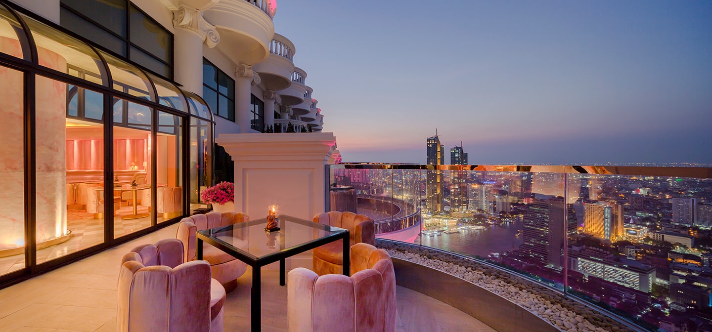 rooftop balcony pink chairs around glass table city skyline view