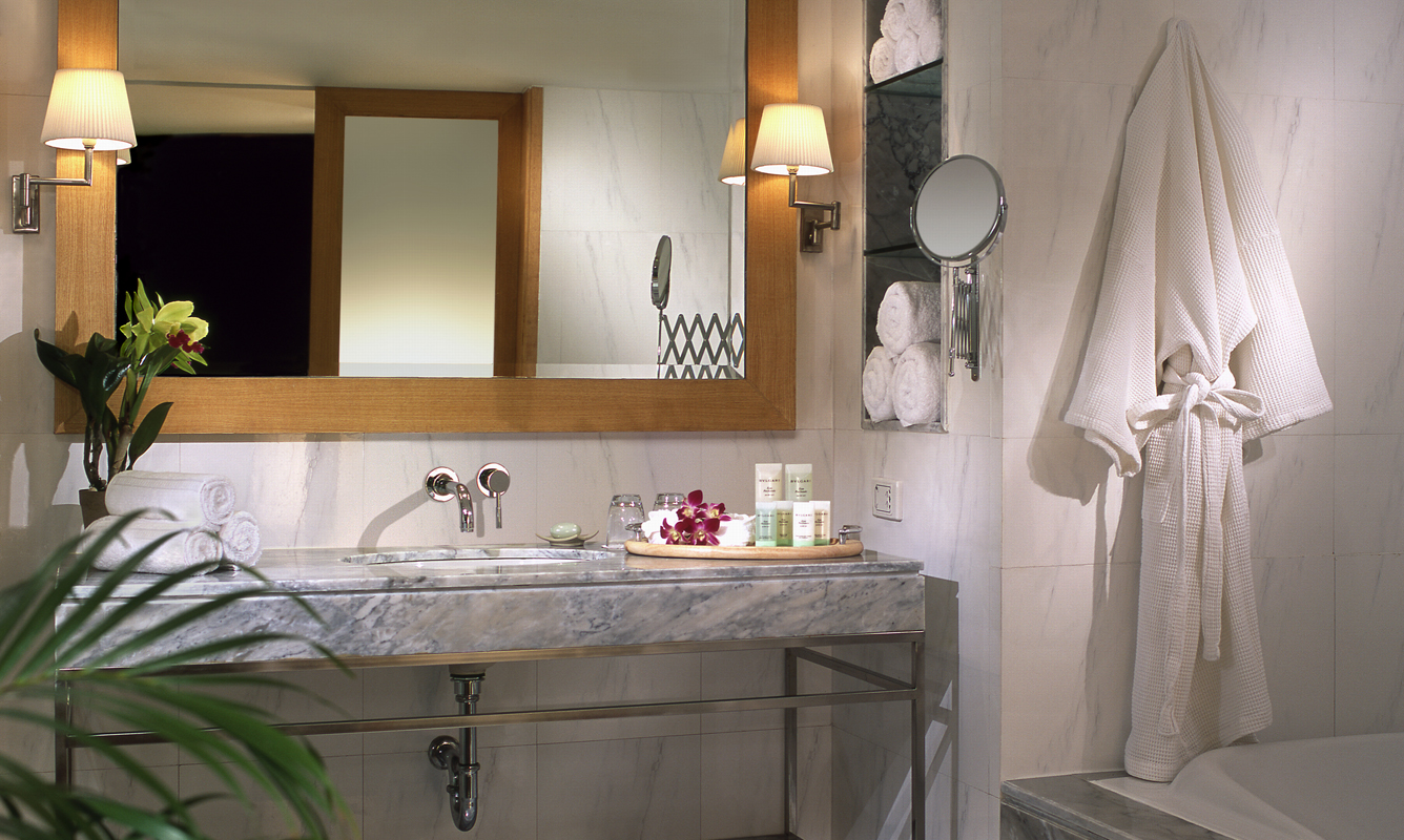 bathroom with marble sink mirror and white bathrobe