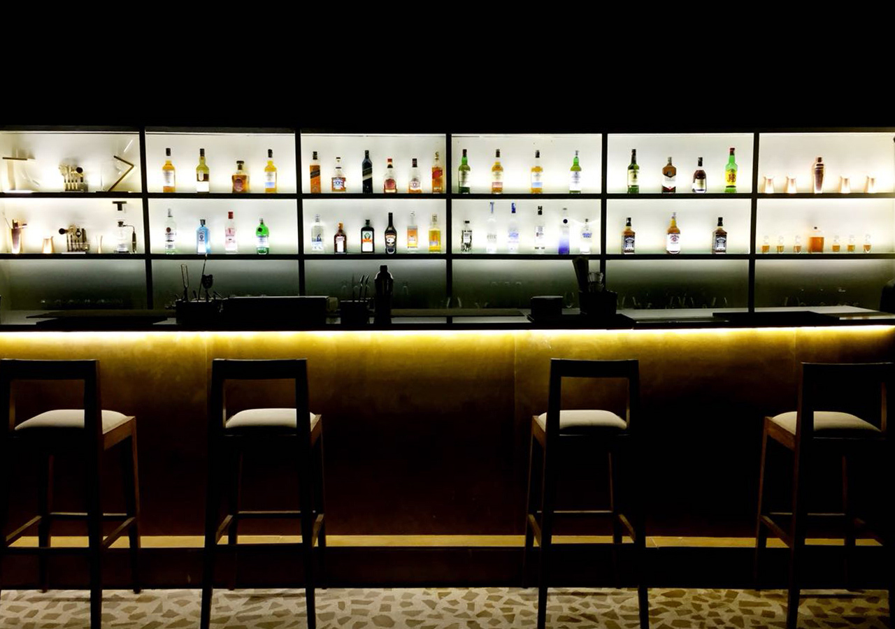 Bottle display seen behind two empty chairs at the bar