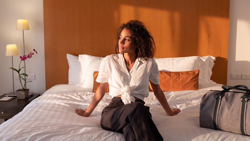 A woman looking out the window while sitting on a large bed