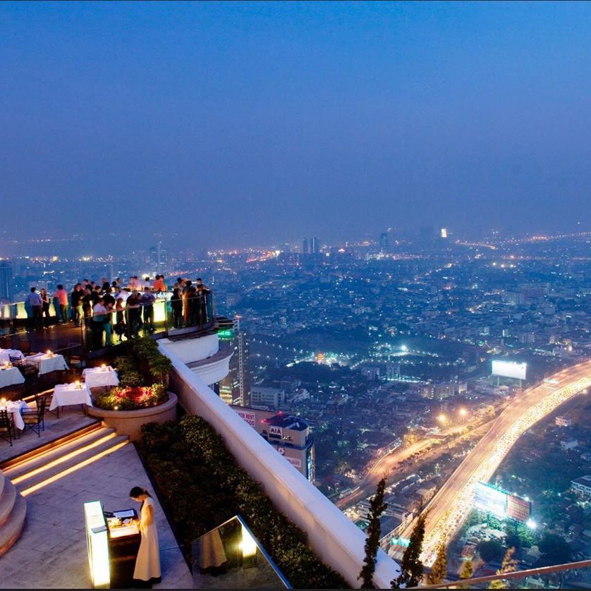 people standing on a rooftop bar and looking at the Bangkok views